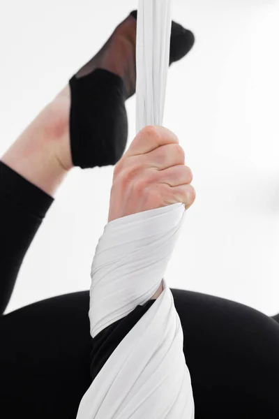 Close-up of a woman's arm wrapped with aerial silks or fabrics, Balance between physical and mental effort concept. Professional aerial performer. Inverted anti-gravity Aerial yoga. Isolated on white.