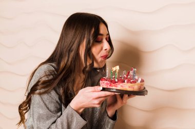 Gri bir arka plan üzerinde izole çikolatalı kek yiyip bitirecek aç genç hamile bir kadın portresi kapatın