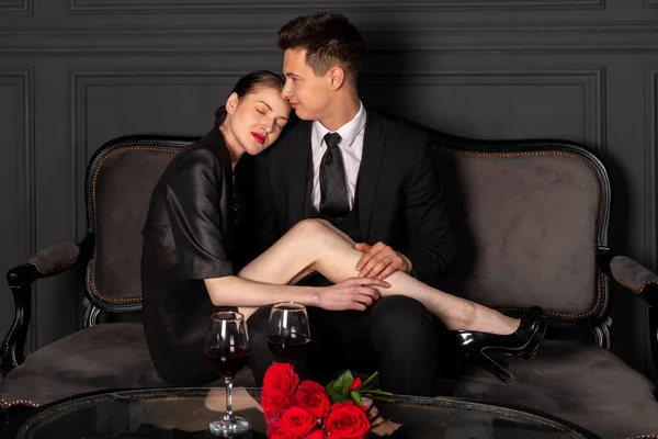 ゴシック様式の美しい暗い部屋のヴィンテージソファでロマンチックな時間を過ごし エレガントでスタイリッシュな服を着た若いカップル ロマンチックなデートだ — ストック写真