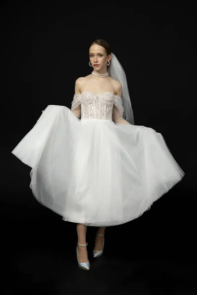 Stock image Close-up Portrait of a beautiful charming girl, the bride in a luxurious and elegant white wedding dress, poses and gesturing tenderly. Isolated on a black background.