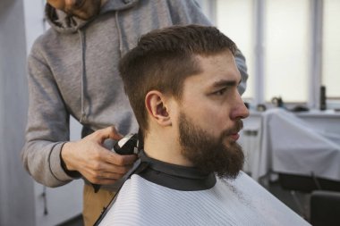 Bir kuaför ya da berber saçında tıraş makinesiyle çalışıyor..