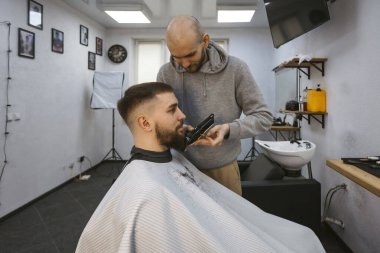 Bir berber müşterisinin sakalı üzerinde çalışıyor..