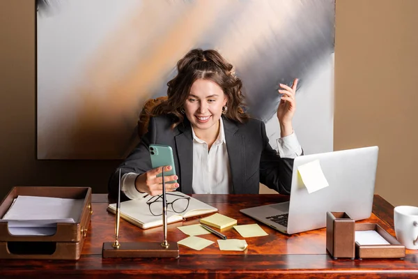 Piękna Bizneswoman Formalnie Ubrana Siedzi Swoim Biurze Telefonem Rękach Mając — Zdjęcie stockowe