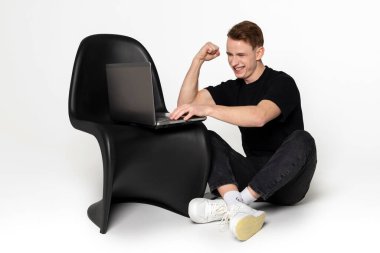 Modern cihazlara ve teknolojiye bağımlı genç bir adam. Çevresindeki dünyayı fark etmeden telefonunu ve laptopunu kullanıyor. Beyaz arkaplanda izole.