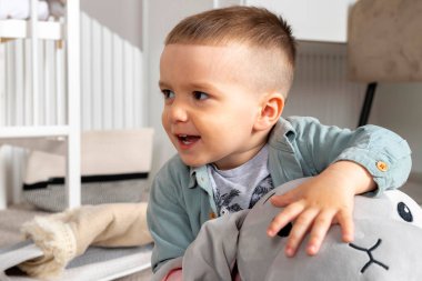 Küçük bebek pelüş oyuncaklarla oynuyor ve gülümsüyor, gülüyor..