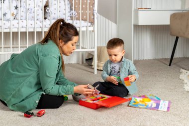 Bir anne ve küçük oğlu bir çocuk odasında oyuncaklarla oynuyor ve renkli kitaplar okuyorlar. Bebek ve dadı birlikte vakit geçiriyorlar..