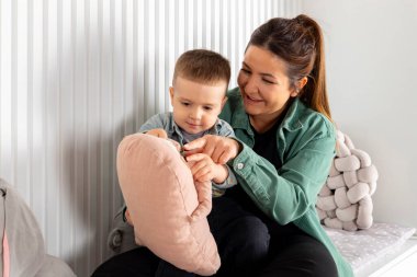 Bir anne ve küçük oğlu bir çocuk odasında oyuncaklarla oynuyorlar. Bebek ve dadı birlikte vakit geçiriyorlar..
