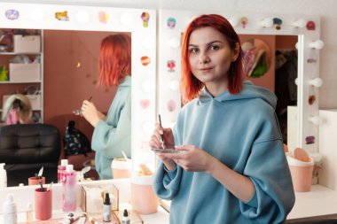 Makyaj sanatçısı ya da vizör küçük cam bir palette boya karıştırıyor..