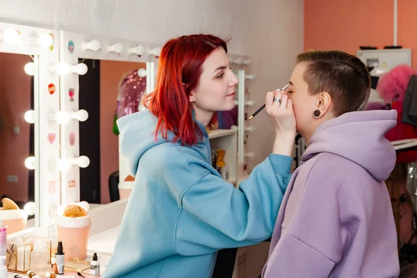 makeup artist or visagiste working on a woman\'s brows in a studio, paints the eyebrows.