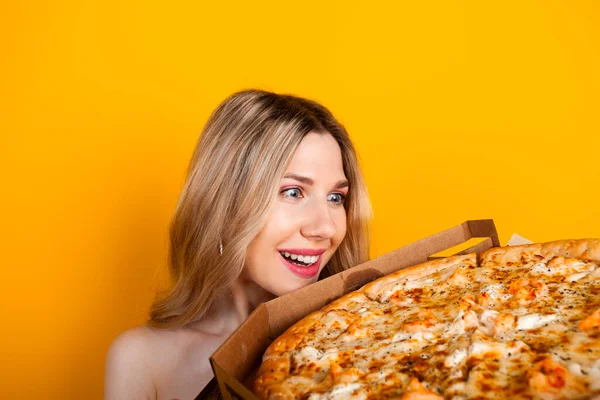 stock image A beautiful fit young blonde girl with a big open pizza box. Isolated on yellow.