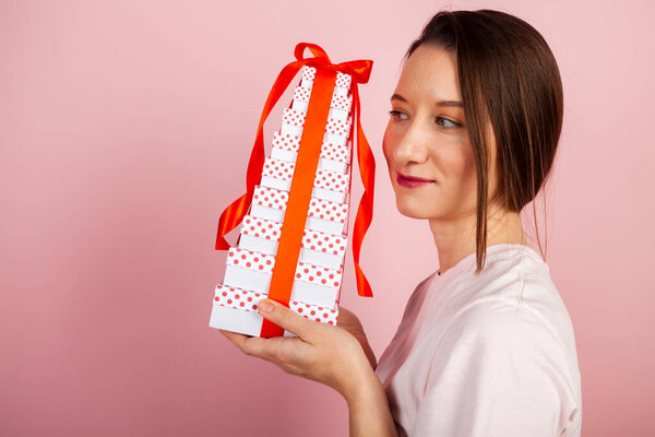 A cute brunette with a stack of beautiful gifts. A girl with gift boxes or presents and ribbons in her hands.