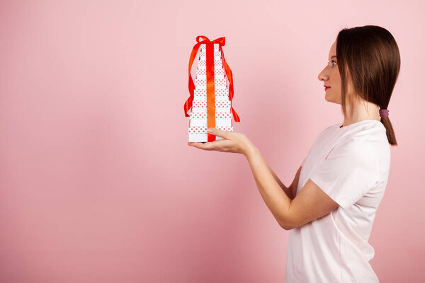 Симпатичная брюнетка со стопкой красивых подарков. Девушка с подарочными коробками или подарками и лентами в руках.