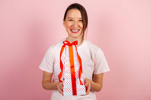 A cute surprised and excited brunette with a stack of beautiful gifts. A girl with gift boxes or presents and ribbons in her hands.