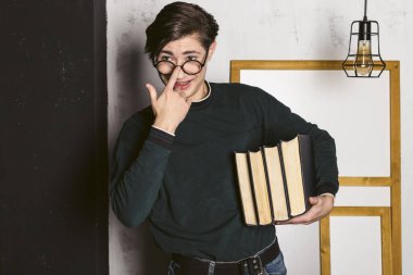 Düzgün giyinmiş, yuvarlak gözlüklü, elinde bir yığın kitapla çalışkan bir genç adam..