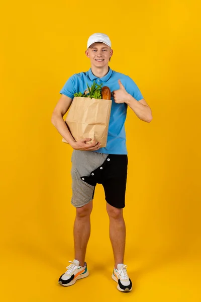 Ung Man Blå Shirt Och Mössa Håller Papperspåse Med Mat — Stockfoto