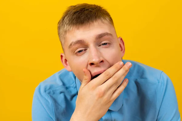 stock image Yawning young man in a blue t-shirt. isolated on yellow.