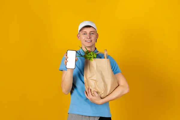 Młody Człowiek Niebieskiej Koszulce Czapce Trzyma Papierową Torbę Jedzeniem Odizolowany — Zdjęcie stockowe