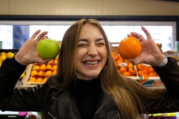 Markette meyve tutan mutlu, gülümseyen genç bir kadının portresi. Sağlıklı beslenme ve yaşam tarzı.