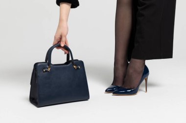 Çekici, zarif bir kızın bacakları ve uzanan bir el çantası..