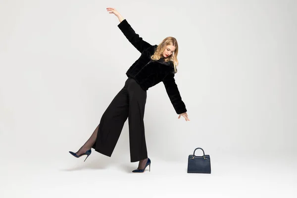 若いCurlyブロンドの女の子はエレガントな服を着て 後ろに傾いて 床のハンドバッグに手を伸ばしています 高価な服 スタイル ファッションのコンセプト — ストック写真