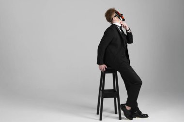 Sivri siyah takım elbiseli şık genç adam parlak bir yüz maskesi takıyor. Gizli kimlik ve kişilik. Gizli niyetler. Kimlik değiştirme. Beyaz arkaplanda izole.