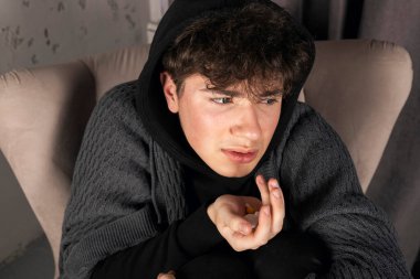 Elinde haplar ve ilaçlarla koltukta oturan depresif bir adam. Zihinsel sorunları olan genç bir adam..