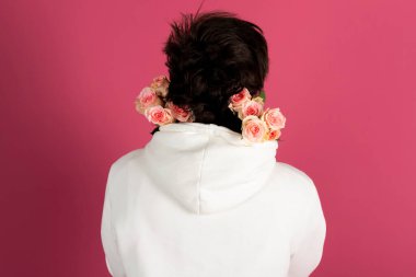 Omuzlarında bir buket çiçekle beyaz kapüşonlu mutlu genç adam. Adam randevuya gidiyor. Dikiz aynası. Pembe üzerine izole edilmiş..