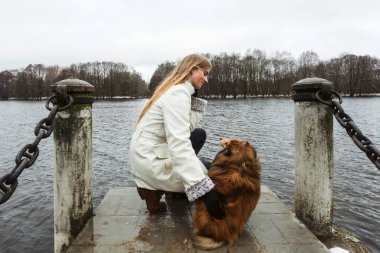 Genç sarışın bir kız ve minyatür Sheltie köpeği küçük iskele ya da rıhtımda durur ve bir kış günü akan bir nehrin mesafesine bakarlar. Güçlü dostluk ve doğanın keyfi.