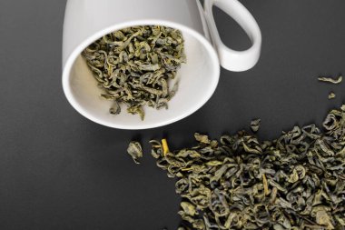 Beyaz bir fincan ya da bardak ve cam bir kavanoz dökülmüş yaprak çayıyla yan yana yatıyorlar.