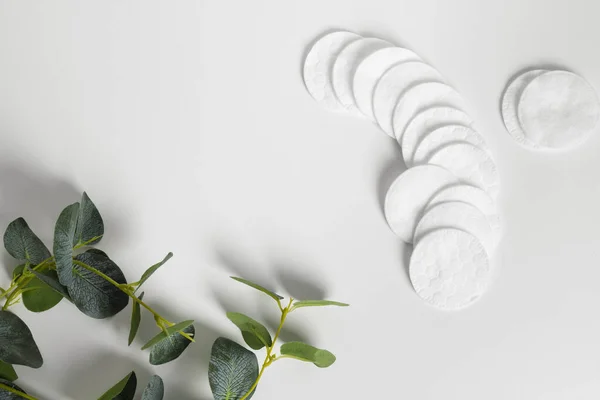 stock image Cotton pads decorated with a plant leaves lying on a white background. flat lay, top view, copy space.