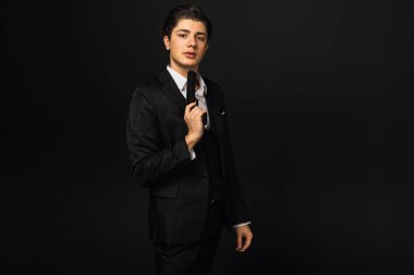 Siyah takım elbiseli, kulağının arkasında puro, silah ya da tabanca tutan genç bir mafya üyesinin portresi. İtalyan mafyası. Siyah arkaplanda izole.