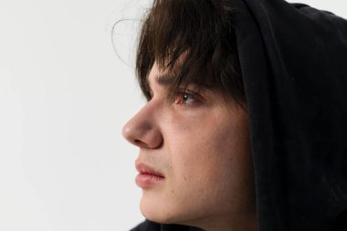 Gözlerinin altında kirli, yırtık pırtık giysiler içinde çürükleri olan genç bir evsizin yakın plan portresi. Beyaz arkaplanda izole.