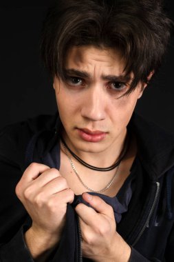 Gözlerinin altında kirli, yırtık pırtık giysiler içinde çürükleri olan genç bir evsizin yakın plan portresi. Siyah arkaplanda izole.