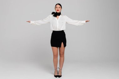 Çekici genç bir hostesin portresi. Çekici, güler yüzlü, seksi üniformalı, el kol kanatlı hostes. Beyaz arkaplanda izole.