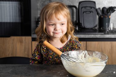 Mutfakta annesine yardım eden, hamuru karıştıran küçük tatlı bir kızın portresi..