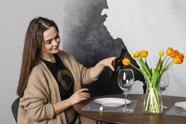 stock image Beautiful brunette woman pours herself some wine