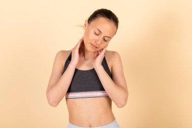 Spor giyim bölümündeki zayıf, tatlı esmer kız. Genç sporcu aktivitelerden önce gerinir. Pastel portakalda izole edilmiş, şeftali arkaplan.