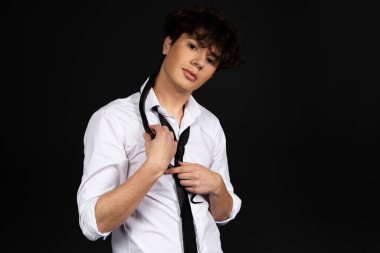 Omzunda siyah bir yılan olan beyaz gömlekli genç yakışıklı bir adam. Siyah arkaplanda izole.