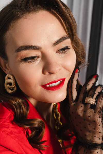 Close-up portrait of a Elegant brunette lady with curly hair in red clothes, polka dot sheer lace gloves. Head shot.