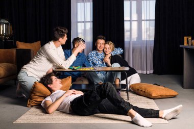 Beş arkadaş birlikte vakit geçiriyorlar, eğleniyorlar, masa oyunları oynuyorlar ve fast food ve abur cubur yiyorlar. Oturma odasında küçük bir arkadaş grubu..