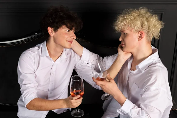 Two young guys celebrating with a bottle of champagne. Romantic evening of the gay couple. blonde and brunette having fun together.