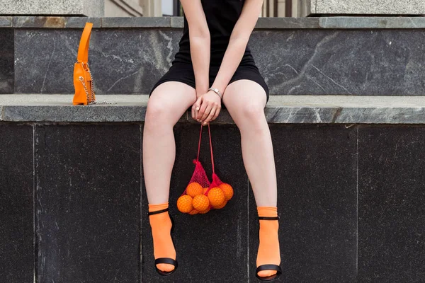 Giyim kuşamında ve makyajında belirgin turuncu unsurları olan güzel, modaya uygun genç bir kız sokakta poz veriyor..