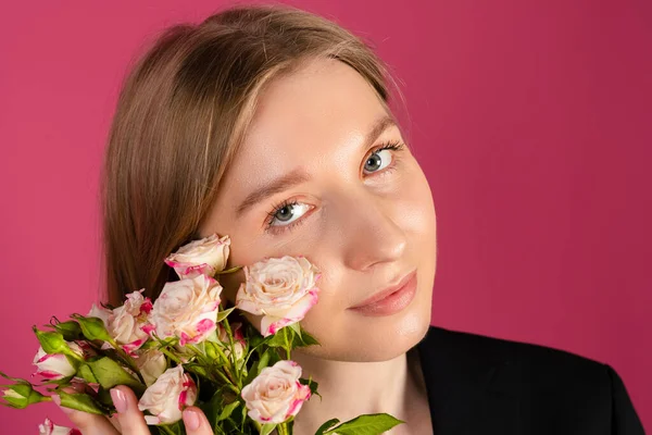 stock image Beautiful tender young blonde hair girl in black blazer holds flowers. isolated on pink background.