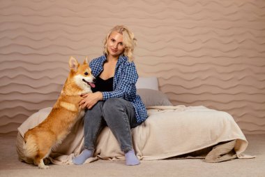 Çekici sarışın kız ve Galli Corgi Pembroke köpeği sarılıyorlar..