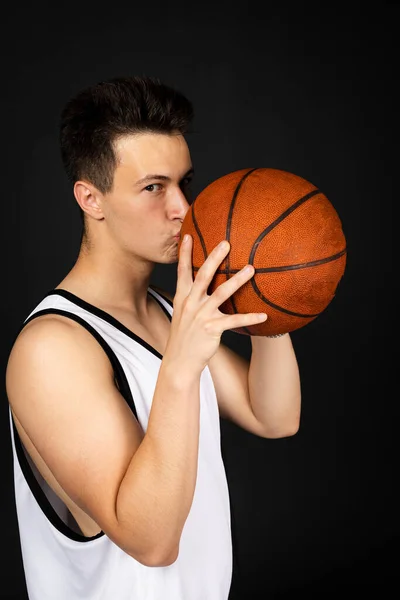 Przystojny Młody Koszykarz Białej Odzieży Sportowej Całuje Piłkę Odizolowany Czarnym — Zdjęcie stockowe