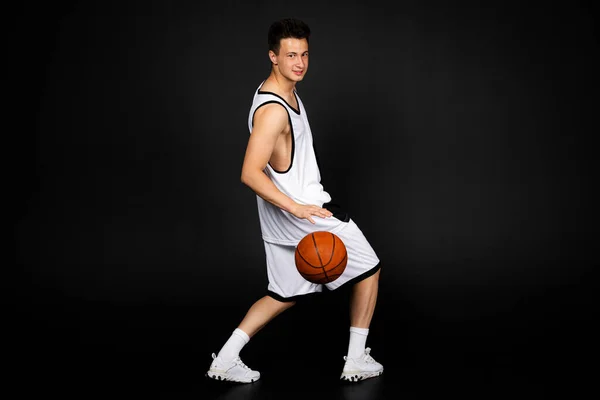Hezký Mladý Basketbalista Bílém Sportovním Oblečení Drží Míč Izolované Černém — Stock fotografie
