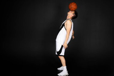 Minsk, Belarus - 22 Mayıs 2023 - Beyaz spor giyimli yakışıklı genç basketbolcu, topla tam boy. Siyah arkaplanda izole.