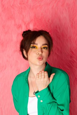 Çekici, güzel bir kız. Parlak makyajlı, çift katlı çörek saçlı, duygusal, yüz ifadesi pembe kürklü arka planda.