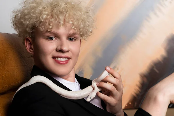 スタイリッシュなブロンドの髪の若い男とLeucistic Ball Python サラリーマンの手にある純白の蛇 — ストック写真