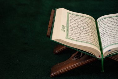 Kur 'an' ı, koyu yeşil bir halıya yerleştirilmiş, ahşap bir stantta açın. Dini bloglar, İslami içerik, Ramazan ve günlük dualar sırasında eğitim için ideal